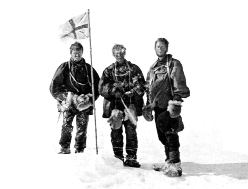 - Professor David (centre), flanked by his companions Mackay and Mawson, stand at the South Magnetic Pole, 16 January 1909. This is an incredibly important historic photo, one of only a few that survives from their great journey. Of course, if you like, it’s also a ‘selfie’ – you can just make out the string that David is pulling to fire the camera’s shutter. Credit: Courtesy Huw Lewis-Jones.   - Professor David’s great grand-daughter, Jenny Gardner, photographed in the hut at Cape Royds, 2015. Credit: Courtesy Huw Lewis-Jones. 